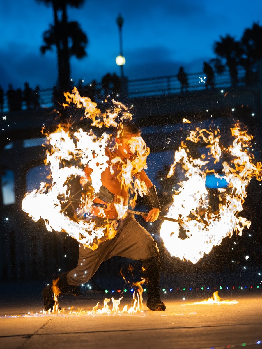 Garrett Brown performing fire on a boardwalk at dusk